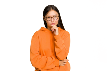 Young Asian woman isolated on green chroma background suspicious, uncertain, examining you.