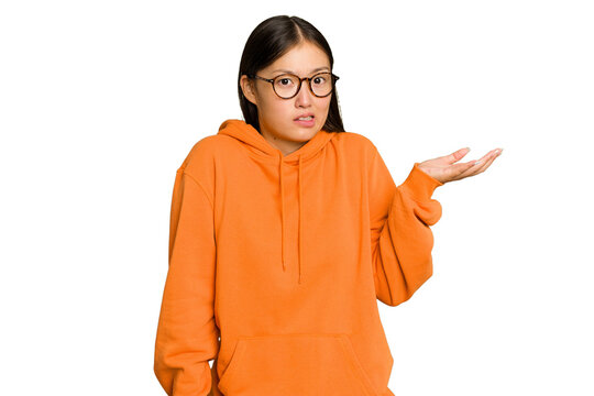 Young Asian woman isolated on green chroma background doubting and shrugging shoulders in questioning gesture.