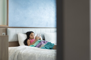 asian child or kid girl sleep lying pillow on bed for playing smartphone or addicted looking mobile...
