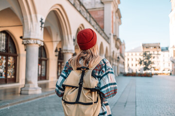 Walking young adult caucasian woman traveller backpack. People traveling in city lifestyle old town street market Krakow, Poland. 