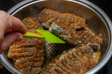 The cook fries fresh crucian fish in a frying pan	
