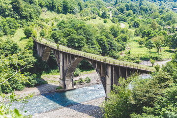 Fototapeta na wymiar Abandoned railway bridge. Mountain landscape with a stone bridge over the river. Abkhazia. 
