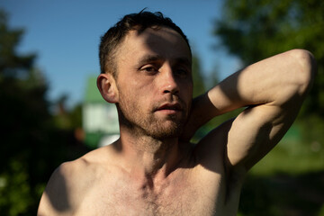 Guy on beach in summer. Man prepares to swim in lake. Guy took off his t-shirt.