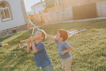 Children blow bubbles in the backyard.