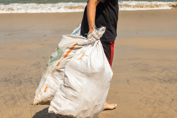 hombre limpia la playa recogiendo bolsas de basura llenas de plástico. Bahia Balaga, Colombia.