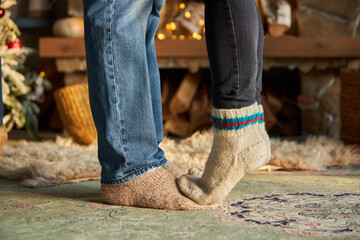 man and woman legs in woolen socks against the background of a fireplace. Home comfort and warmth....