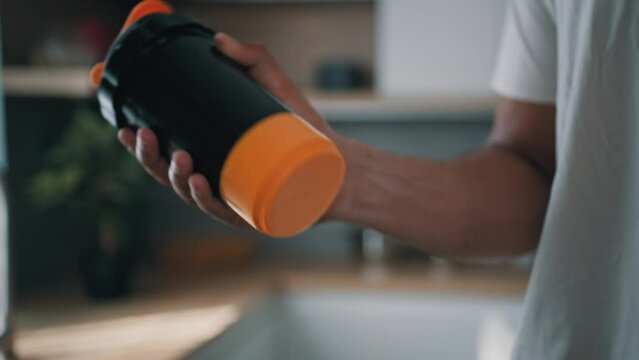 Unrecognizable African American strong sport man male athlete indoors shaking bottle shaker with liquid calcium mixing protein cocktail sports supplements healthy nutrition bodybuilding fitness diet