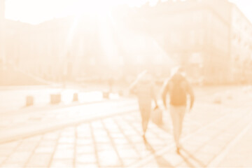 Blurred background of a couple walking in the city on a sunny day. Copy space for text. Toned photo in warm orange color.