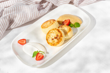 Cottage cheese pancakes with sour cream, raspberries and mint on a plate on the table. Homemade dessert. Top view