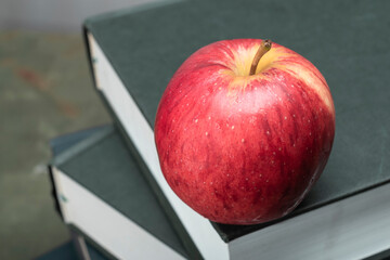 Apple on stack of book on green wood table study.