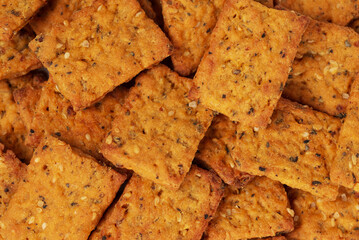 Whole grain square vegetable crackers with spices and seeds as food background