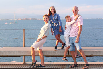 mom, dad, daughter and son happy family on sea marina background