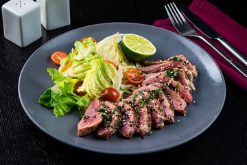 Juicy steak medium rare beef with green salad on plate