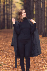 a blonde woman in an autumn park takes off her gray coat. autumn mood foliage