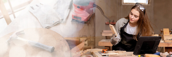 Web banner Portrait of a female carpenter looking at designs on a laptop for making her furniture in a furniture factory. with many tools and wood with copy space on left