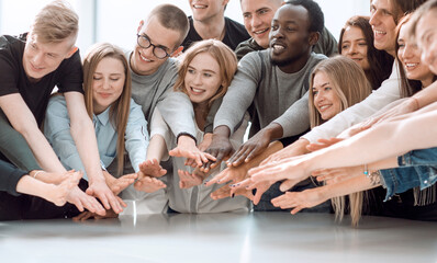 group of smiling young people joining their hands