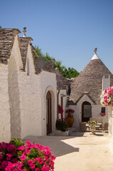 houses with cone roof, white walls with lime and stone on the roof, flower pots and plants, clear skies, harmony and simplicity