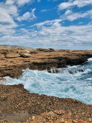 Jetty with sea waves moving with blue sky and clouds