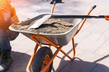 construction wheelbarrow with sand and shovel - obrazy, fototapety, plakaty