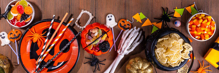 Halloween sweets and snacks table. Set of Halloween dinner party foods, candy, snacks, with holiday costume decorations, pumpkin buckets, wooden background top view copy space © ricka_kinamoto