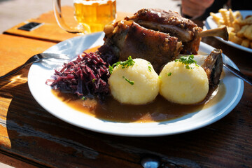 Crusty knuckle of pork with dumplings and cabbage in a beer garden. Traditional oktoberfest food...