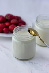 Homemade yogurt. Jars of yogurt and strawberries on a white table. Proper nutrition