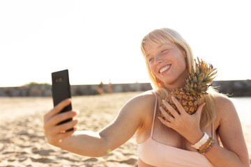 Cheerful young woman enjoy at tropical sand beach. Young woman taking selfie photo...