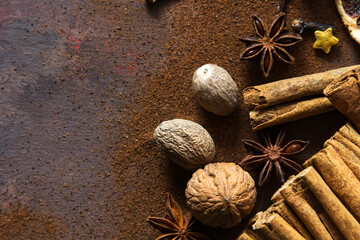 Christmas spices. Christmas composition with cinnamon sticks; anise stars, nutmeg, cloves and hazelnut on dark background. Copy space for your text. Rustic vibe.
