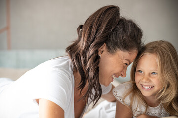 Mother and daughter reading book together on bed in bedroom
Having fun together, smiling 