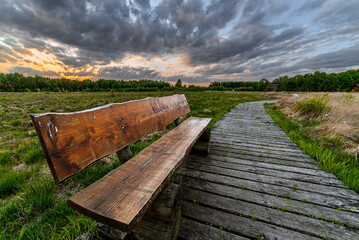 Fototapeta Eine schöne Holzbank im Goldenstedter Moor zum Sonnenuntergang obraz
