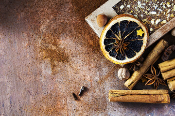 Fototapeta na wymiar Christmas chocolate with orange peel and spices. Composition with cinnamon sticks; anise stars, nutmeg, cloves, hazelnut and dried orange slices on dark background. Copy space for your text.