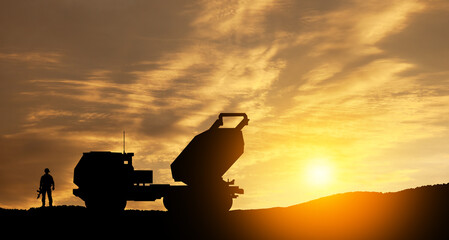 Artillery rocket system are aimed to the sky and soldier at sunset. Multiple launch rocket system....