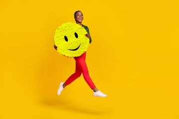 Full length photo of adorable impressed woman wear green shirt holding smiley jumping empty space isolated yellow color background
