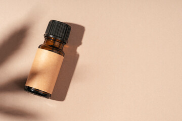 Amber bottle with cannabis oil used for medical purposes on beige background. Daylight and the shadow of a hemp leaf. Soothing cbd oil. Alternative Medicine. Copy space