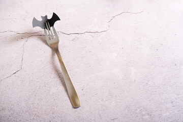 Iron fork with bat in teeth on a light concrete table