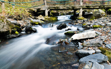 Fototapeta na wymiar Old wooden bridge over small stream water