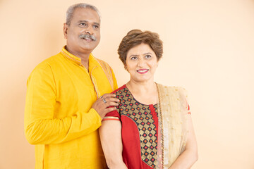 Portrait of senior indian couple wearing traditional cloths standing together isolated on plane studio background.