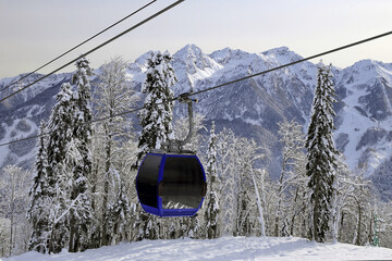 Cable car lift cabin on snowy Caucasus mountain peaks background. Scenic winter landscape at ski resort.