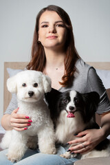 Happy girl holding cute bichon and papillon dogs.