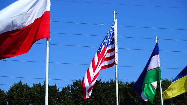 Flags of Poland, USA, Uzbekistan and Ukraine on flagpoles.