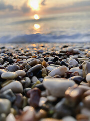 View of the sea and sun rising above the stones in Cirali, Antalya, Turkey. Selective focus.