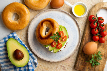 Toasted baggel with cream cheese, avocado and organic cherry tomatoes. Vegan brunch.