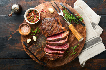Steaks. Sliced grilled meat steak New York or Striploin with spices rosemary and pepper on black...
