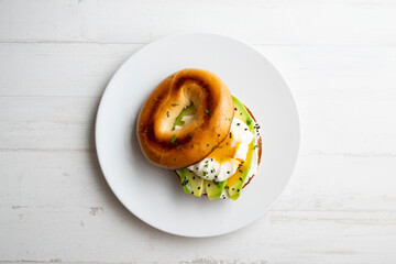 Toasted baggel with cream cheese, avocado, organic cherry tomatoes and poached egg. Vegan brunch.