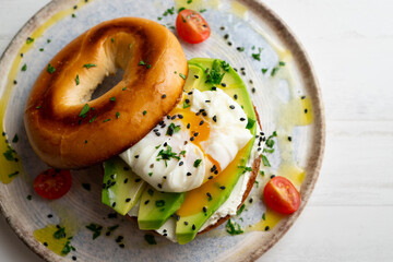 Toasted baggel with cream cheese, avocado, organic cherry tomatoes and poached egg. Vegan brunch.