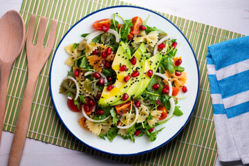 Argula salad with pasta bows, avocado, cherry tomatoes, pomegranate and sesame.