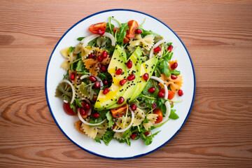 Argula salad with pasta bows, avocado, cherry tomatoes, pomegranate and sesame.