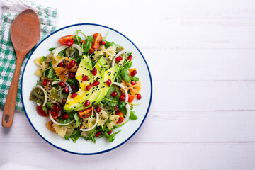 Argula salad with pasta bows, avocado, cherry tomatoes, pomegranate and sesame.
