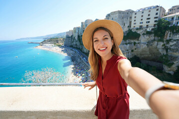 Selfie girl in Tropea, Italy. Young tourist woman taking self portrait with Tropea village on Coast...