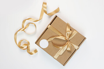 The gift box is made of craft cardboard. The box is tied with a beige satin ribbon. Flat lay.View from above.Space for copying.Packaging for gifts. An empty label for the label.